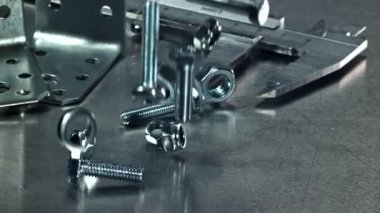 Metal bir masaya düşen somunlar, civatalar ve çamaşır makineleri. 1000 fps 'de yüksek hızlı bir kamerayla çekildi. Yüksek kaliteli FullHD görüntüler