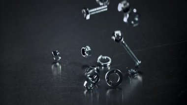 Metal bir masaya düşen somunlar, civatalar ve çamaşır makineleri. 1000 fps 'de yüksek hızlı bir kamerayla çekildi. Yüksek kaliteli FullHD görüntüler