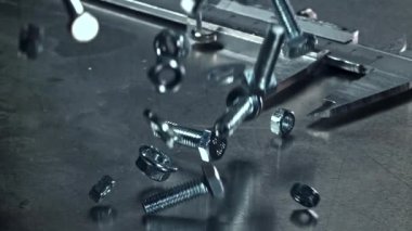 Metal bir masaya düşen somunlar, civatalar ve çamaşır makineleri. 1000 fps 'de yüksek hızlı bir kamerayla çekildi. Yüksek kaliteli FullHD görüntüler
