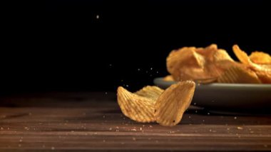 Patates cipsi ahşap masaya düşer. 1000 fps 'de yüksek hızlı bir kamerayla çekildi. Yüksek kaliteli FullHD görüntüler