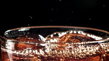 Bir bardak buzlu kola. Yüzeyde sıçramalar var. 1000 fps 'de yüksek hızlı bir kamerayla çekildi. Yüksek kaliteli FullHD görüntüler