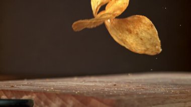 Patates cipsi ahşap masaya düşer. 1000 fps 'de yüksek hızlı bir kamerayla çekildi. Yüksek kaliteli FullHD görüntüler