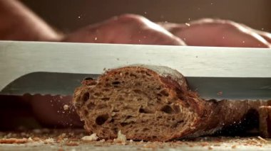 Şef ekmek dilimler. Taze baget dilimlenmiş. 1000 fps 'de yüksek hızlı bir kamerayla çekildi. Yüksek kaliteli FullHD görüntüler