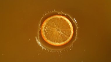 Meyve suyuna bir dilim portakal düşer. 1000 fps 'de yüksek hızlı bir kamerayla çekildi. Yüksek kaliteli FullHD görüntüler