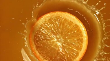 Meyve suyuna bir dilim portakal düşer. 1000 fps 'de yüksek hızlı bir kamerayla çekildi. Yüksek kaliteli FullHD görüntüler