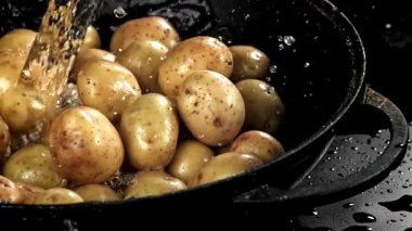 Su taze patateslerin üzerine dökülür. 1000 fps 'de yüksek hızlı bir kamerayla çekildi. Yüksek kaliteli FullHD görüntüler