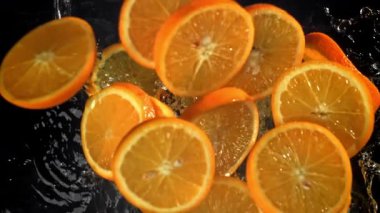 Dilimlenmiş turuncu daireler suya düşer. 1000 fps 'de yüksek hızlı bir kamerayla çekildi. Yüksek kaliteli FullHD görüntüler