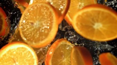 Dilimlenmiş turuncu daireler suya düşer. 1000 fps 'de yüksek hızlı bir kamerayla çekildi. Yüksek kaliteli FullHD görüntüler
