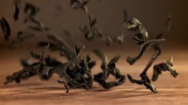 Kuru çay yaprakları ahşap bir masaya düşer. 1000 fps 'de yüksek hızlı bir kamerayla çekildi. Yüksek kaliteli FullHD görüntüler