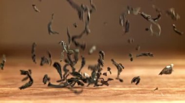 Kuru çay yaprakları ahşap bir masaya düşer. 1000 fps 'de yüksek hızlı bir kamerayla çekildi. Yüksek kaliteli FullHD görüntüler