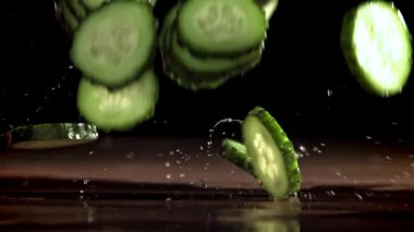 Dilimlenmiş salatalıklar masaya düşer. 1000 fps 'de yüksek hızlı bir kamerayla çekildi. Yüksek kaliteli FullHD görüntüler