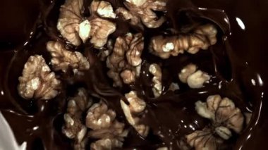 Cevizler sıvı çikolatanın içine düşer. 1000 fps 'de yüksek hızlı bir kamerayla çekildi. Yüksek kaliteli FullHD görüntüler