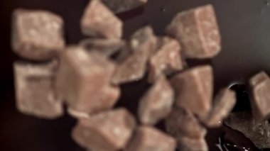 Çikolata parçaları erimiş çikolatanın içine düşer. 1000 fps 'de yüksek hızlı bir kamerayla çekildi. Yüksek kaliteli FullHD görüntüler