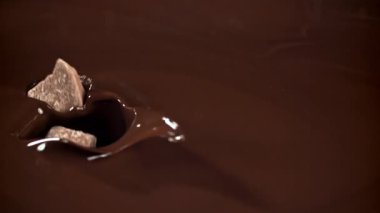 Çikolata parçaları erimiş çikolatanın içine düşer. 1000 fps 'de yüksek hızlı bir kamerayla çekildi. Yüksek kaliteli FullHD görüntüler