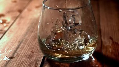 Buz bir bardak viskinin içine düşer. 1000 fps 'de yüksek hızlı bir kamerayla çekildi. Yüksek kaliteli FullHD görüntüler
