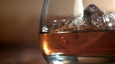 Buz bir bardak viskinin içine düşer. 1000 fps 'de yüksek hızlı bir kamerayla çekildi. Yüksek kaliteli FullHD görüntüler