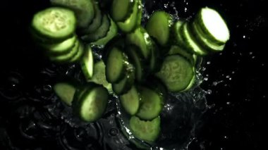 Dilimlenmiş salatalıklar suya düşer. 1000 fps 'de yüksek hızlı bir kamerayla çekildi. Yüksek kaliteli FullHD görüntüler