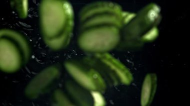 Dilimlenmiş salatalıklar suya düşer. 1000 fps 'de yüksek hızlı bir kamerayla çekildi. Yüksek kaliteli FullHD görüntüler