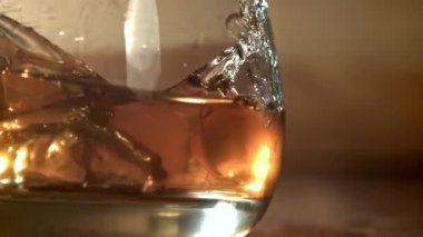 Buz bir bardak viskinin içine düşer. 1000 fps 'de yüksek hızlı bir kamerayla çekildi. Yüksek kaliteli FullHD görüntüler