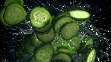 Dilimlenmiş salatalıklar suya düşer. 1000 fps 'de yüksek hızlı bir kamerayla çekildi. Yüksek kaliteli FullHD görüntüler