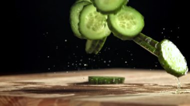 Dilimlenmiş salatalıklar masaya düşer. 1000 fps 'de yüksek hızlı bir kamerayla çekildi. Yüksek kaliteli FullHD görüntüler