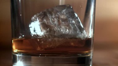 Buz bir bardak viskinin içine düşer. 1000 fps 'de yüksek hızlı bir kamerayla çekildi. Yüksek kaliteli FullHD görüntüler