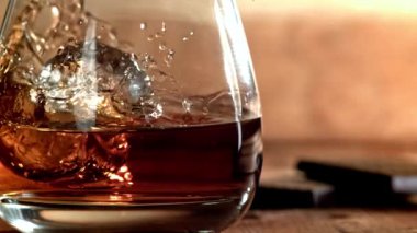 Buz bir bardak viskinin içine düşer. 1000 fps 'de yüksek hızlı bir kamerayla çekildi. Yüksek kaliteli FullHD görüntüler