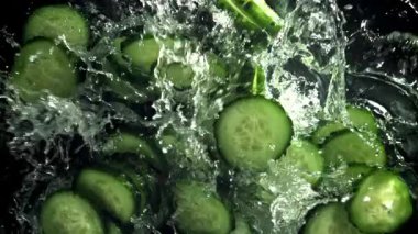 Dilimlenmiş salatalıklar suya düşer. 1000 fps 'de yüksek hızlı bir kamerayla çekildi. Yüksek kaliteli FullHD görüntüler