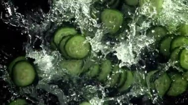 Dilimlenmiş salatalıklar suya düşer. 1000 fps 'de yüksek hızlı bir kamerayla çekildi. Yüksek kaliteli FullHD görüntüler