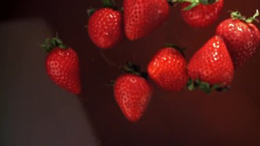 Çilekler çikolatanın içine düşer. 1000 fps 'de yüksek hızlı bir kamerayla çekildi. Yüksek kaliteli FullHD görüntüler