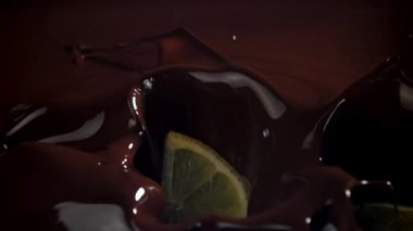 Limon dilimleri çikolatanın içine düşer. 1000 fps 'de yüksek hızlı bir kamerayla çekildi. Yüksek kaliteli FullHD görüntüler