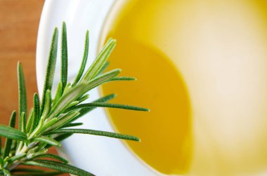 Beyaz bir kâse içinde zeytinyağı ve taze biberiye.                               