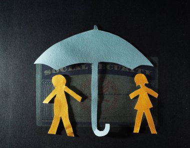 Paper couple with a Social Security card and  paper umbrella -- financial security or retirement savings concept                                clipart