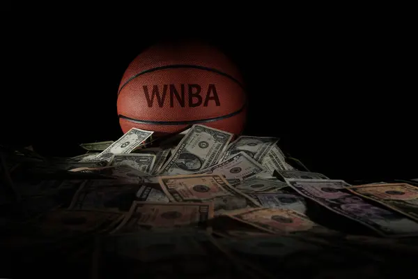 Stock image Raleigh, NC - USA - 04-15-2024: A basketball with WNBA text on a pile of money