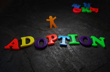 Kağıt kesme çocuğu dokulu arka planda renkli oyun harfleriyle yazılan evlat edinme                               