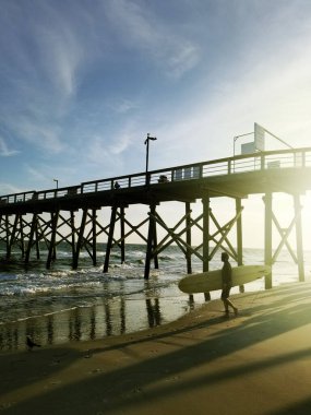 A surfer at the Oak Island pier at sunset, Brunswich County , North Carolina clipart