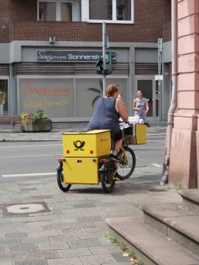 WORMS, GERMANY - CIRCA AUGUST 2022: Postwoman delivering mail by bike