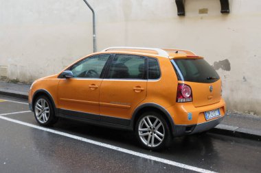 FLORENCE; ITALY - JANUARY 14, 2016: orange Volkswagen Polo car parked in a street of the city centre.