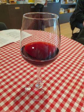 Bir bardak kırmızı şarap. Alkolik. Kareli masa örtüsü üzerinde içki.