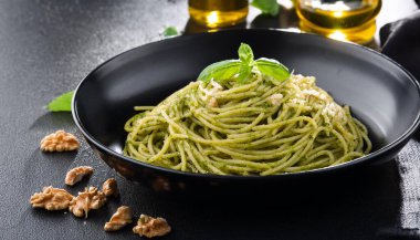 spaghetti al pesto with walnuts and extra virgin olive oil, in a black dish, AI generated image clipart