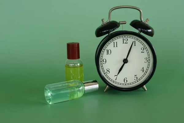 緑の背景に目覚まし時計とボディローション — ストック写真