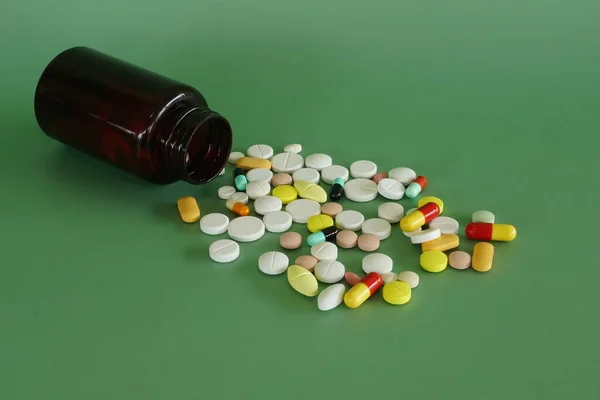 Pillen Mit Behälter Vor Grünem Hintergrund lizenzfreie Stockfotos