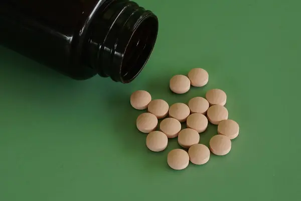 stock image pills with container against green background