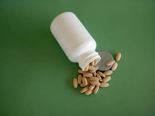 pills with container against green background