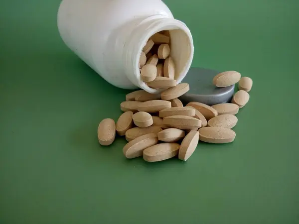 Tabletter Med Beholder Mot Grønn Bakgrunn – stockfoto