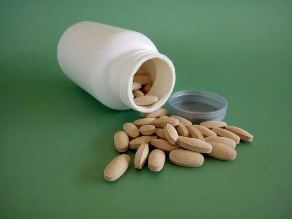 pills with container against green background