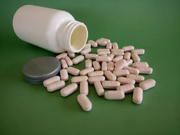 Tabletki Pojemnikiem Zielonym Tle — Zdjęcie stockowe