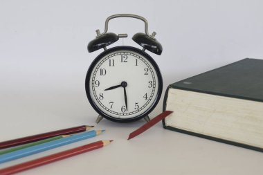 Masanın üzerinde çalar saat olan bir kitap.