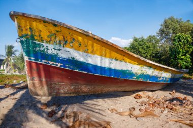 Yalnız bir sahilde dinlenen renkli bir kır teknesi.