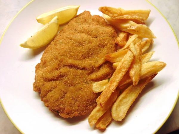 breaded cutlets with french fries and lemon slices as dressing